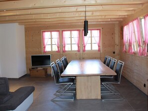 Ein moderner Essbereich mit einem langen Tisch, Stühlen und einem Fernseher.