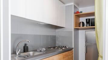 Una cocina compacta con lavamanos, estufa y armarios de madera.