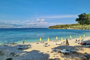 På stranden, hvit sand, parasoller og strandbar