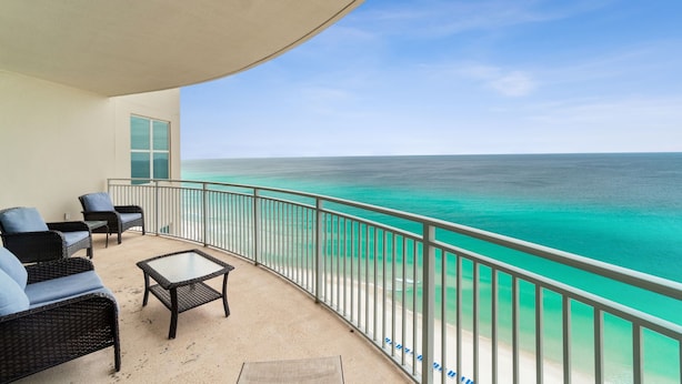 A balcony with wicker furniture and a view of the ocean.