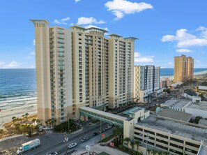 A high-rise hotel with multiple balconies, a parking garage, and a view of the beach. - Beach Service Included | Gulf-Front 15th Floor Condo | Stunning Sunset Views (Panama City Beach)