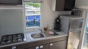 A compact kitchen with a gas stove, sink, and stainless steel refrigerator.
