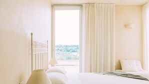 A hotel room with a bed, a bedside table with a lamp, and a view of a green landscape through the window. - Rent room Nontiscordardimè (Civitanova Marche)