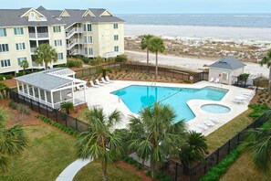 A resort with a large pool, a beach view, and multiple balconies.