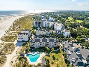 A coastal resort with multiple buildings, a beachfront, and a swimming pool.