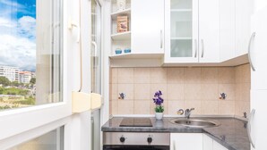 A modern kitchen with white cabinets, a built-in oven, a sink, and a window overlooking a cityscape. - Spacious studio with balcony, close to the Znjan beach (Split)