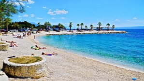 A beach with clear blue water, people sunbathing, and palm trees. - Spacious studio with balcony, close to the Znjan beach (Split)