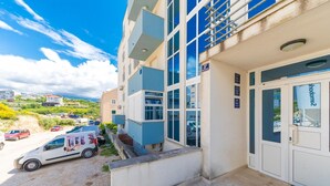 A modern building with a ground-level entrance, a visible parking area, and a clear view of the surrounding landscape. - Spacious studio with balcony, close to the Znjan beach (Split)