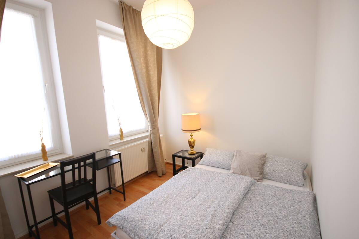 A bedroom with a bed, a desk, and a lamp.