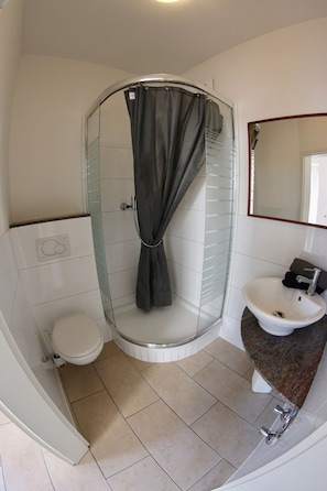 A bathroom with a glass-enclosed shower, a toilet, and a sink with a mirror above it. - a-domo Apartments Essen - Serviced Apartments & Flats - short or longstay - single or grouptravel (Essen)