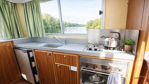 Cocina compacta con fregadero, estufa, horno y ventana con vistas a zonas verdes.