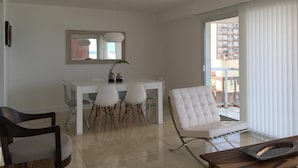 A modern living room with a dining area, a white sofa, and a large window with blinds. - Tranquility and peace, in Maires la Isla (Mar del Plata)