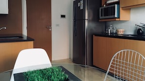 A modern kitchen with a stainless steel refrigerator, wooden cabinets, a black countertop, and a glass table with a green plant. - Tranquility and peace, in Maires la Isla (Mar del Plata)