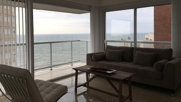A balcony with a view of the ocean, a sofa, and a chair. - Tranquility and peace, in Maires la Isla (Mar del Plata)
