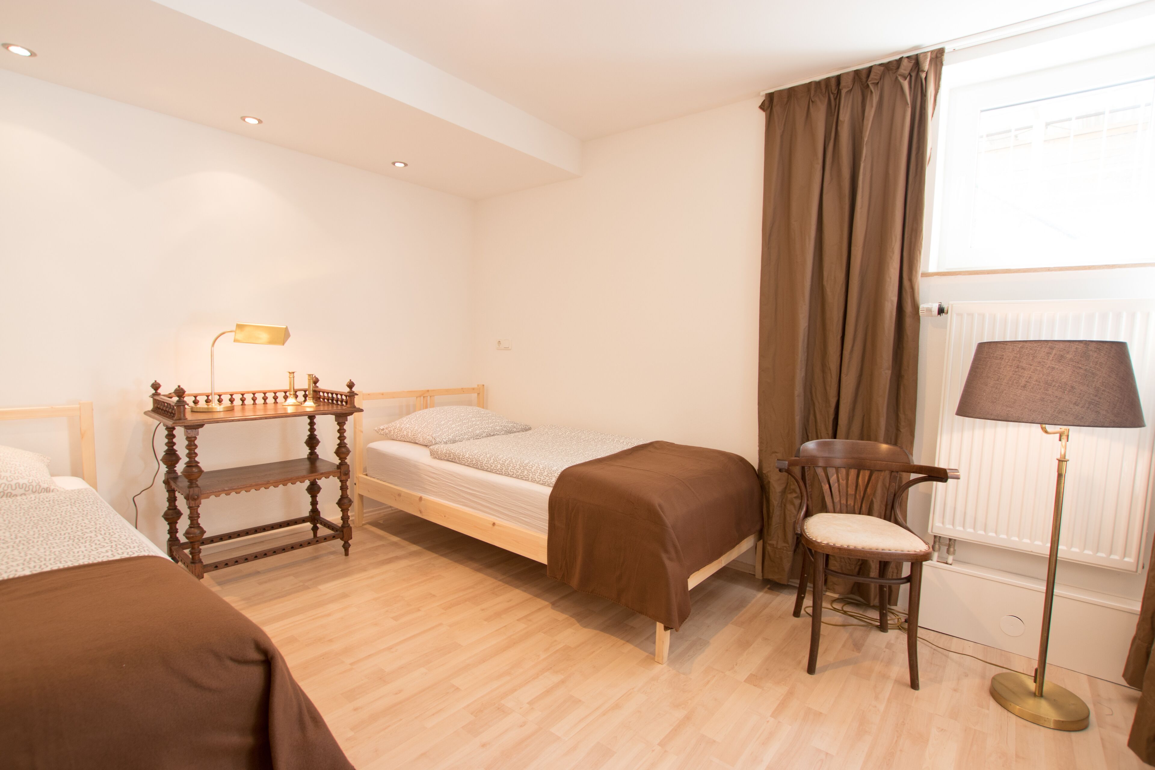Ein Zimmer mit Bett, Sessel, Tisch und Lampe.