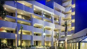 Un hôtel à plusieurs étages doté de balcons, d’une cour aménagée et d’une entrée en verre.