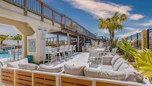Un espace aménagé au bord de la piscine, comprenant un coin salon, un barbecue et un panneau indiquant qu’il est interdit de fumer sur le pont de la piscine.