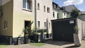 A multi-story residential building with a gated entrance, potted plants, and a paved courtyard. - a-domo Apartments Oberhausen - Budget Apartments & Flats - short & longterm - single & grouptravel (Oberhausen)