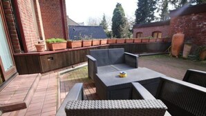 An outdoor patio area with wicker furniture, a brick floor, and a wooden fence. - a-domo Apartments Oberhausen - Budget Apartments & Flats - short & longterm - single & grouptravel (Oberhausen)