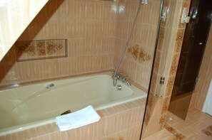 A bathroom with a bathtub, shower, and tiled walls. - la Villa des Longchamps (Saint-Jouan-des-Guérets)