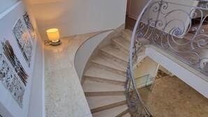 Eine Wendeltreppe mit Metallgeländer, einer Wandleuchte und Wanddekoration.