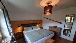 A bedroom with a bed, bedside tables, a mirror, and a hanging light fixture. - Ferienwohnung bis 2 Personen, Erdgeschoss, Terrasse (Grassau)