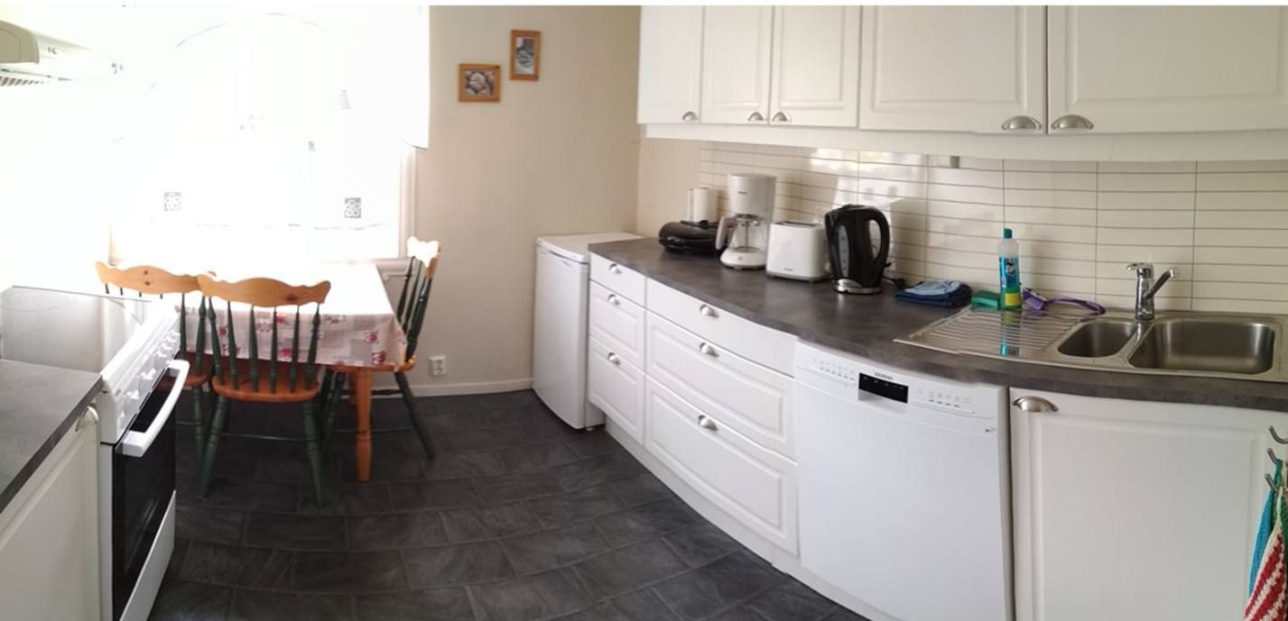 A compact kitchen with white cabinets, a built-in dishwasher, a coffee maker, and a sink.