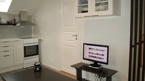 Ett kök med vita skåp, en inbyggd ugn, en dator på ett skrivbord och ett takfönster ovanför arbetsbänken.