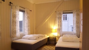 Ein Zimmer mit zwei Betten, einem kleinen Tisch, einer Lampe und einem gemusterten Teppich.