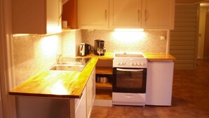 Eine kleine Küche mit Spüle, Herd und Backofen, Holz Arbeitsplatten und weißen Schränken.