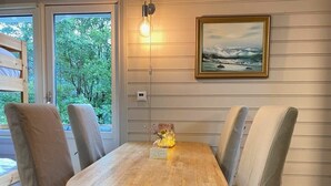 A wooden table with cushioned chairs, a wall-mounted light, and a framed painting. - Kveldsro cabin in nice surroundings (Mosby)