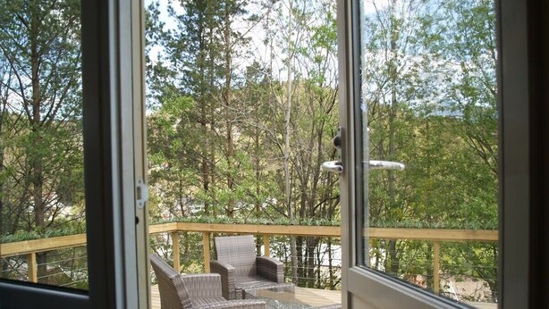 A deck with wicker furniture and a view of a forested area. - Kveldsro cabin in nice surroundings (Mosby)