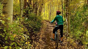 A person riding a bicycle on a dirt path surrounded by trees with yellow leaves. - Quiet location in "Swiss community" near Park City (midway)