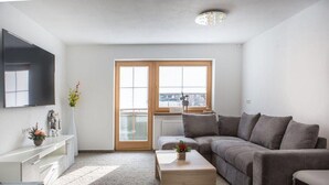 Un salon moderne avec un canapé gris, une table basse en bois et un téléviseur fixé au mur.