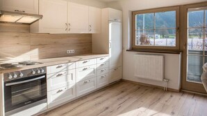 Une cuisine moderne avec des meubles en bois, un four encastré et une fenêtre donnant sur l’extérieur.