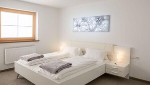 Une chambre à coucher comprenant un lit, deux tables de chevet, une fenêtre et une œuvre d’art accrochée au mur.