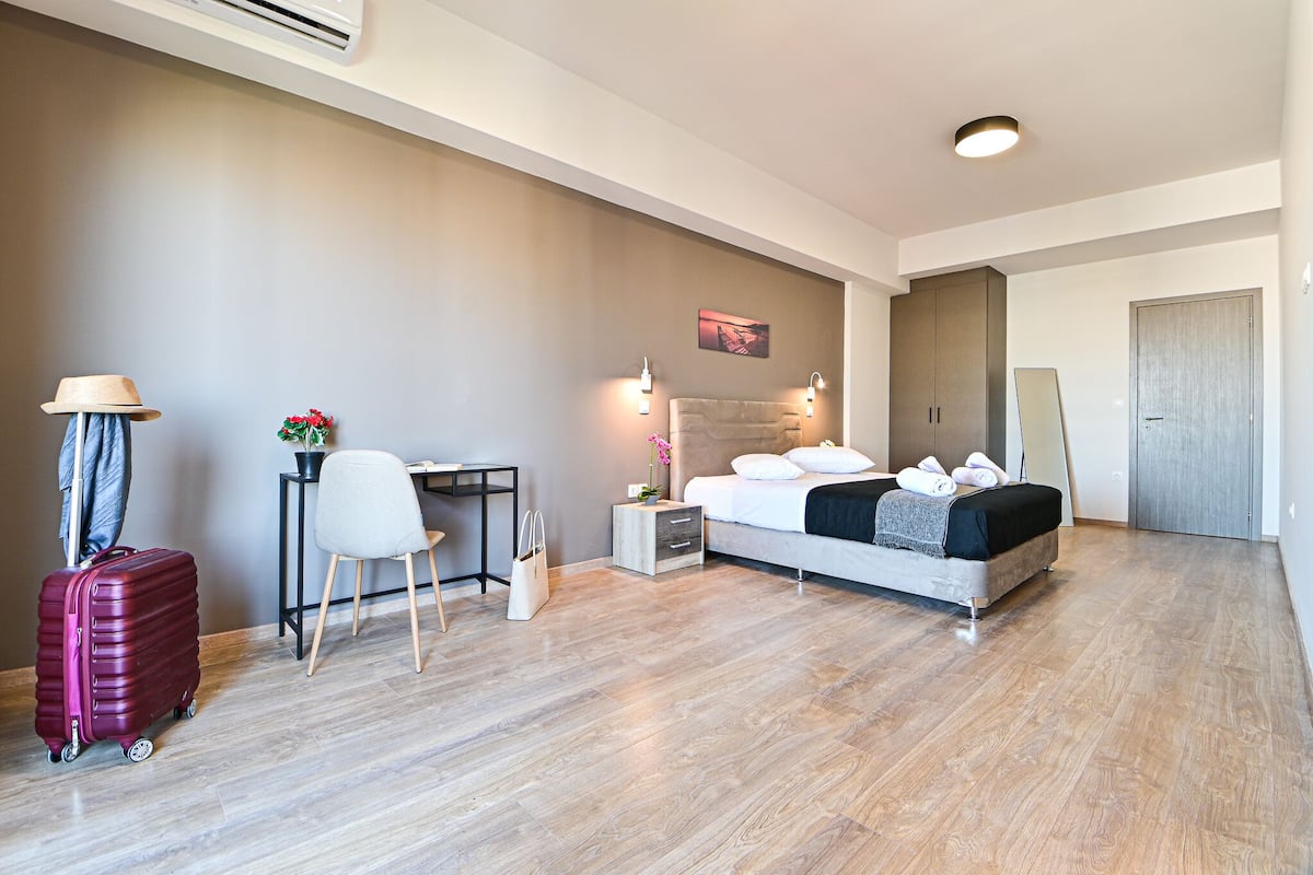 Una habitación de hotel moderna con cama, escritorio, silla y maleta.