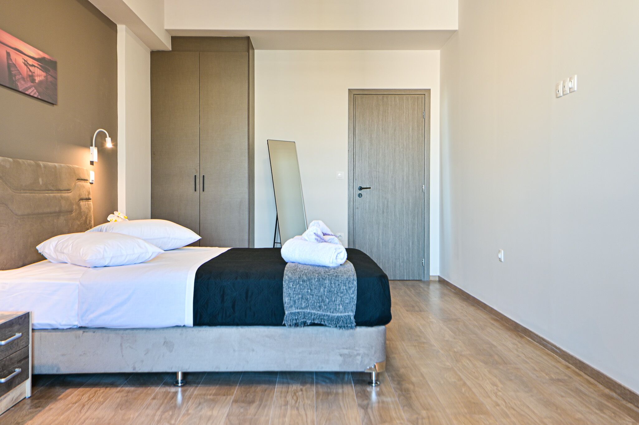 A modern bedroom with a bed, bedside lamp, and a wardrobe.