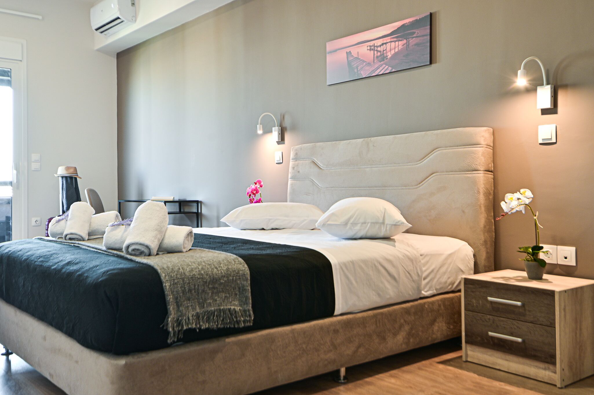 Un dormitorio moderno con una cama grande, mesitas de noche y una lámpara fijada a la pared.