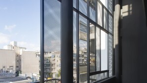 A balcony with a view of the cityscape, metal mesh window frames, and two black chairs. - Thisean Modern Suites by Athens Stay (Kallithea)