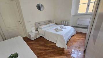 Ein Schlafzimmer mit einem Bett, Nachttischen, einem Heizkörper und einem Fenster.