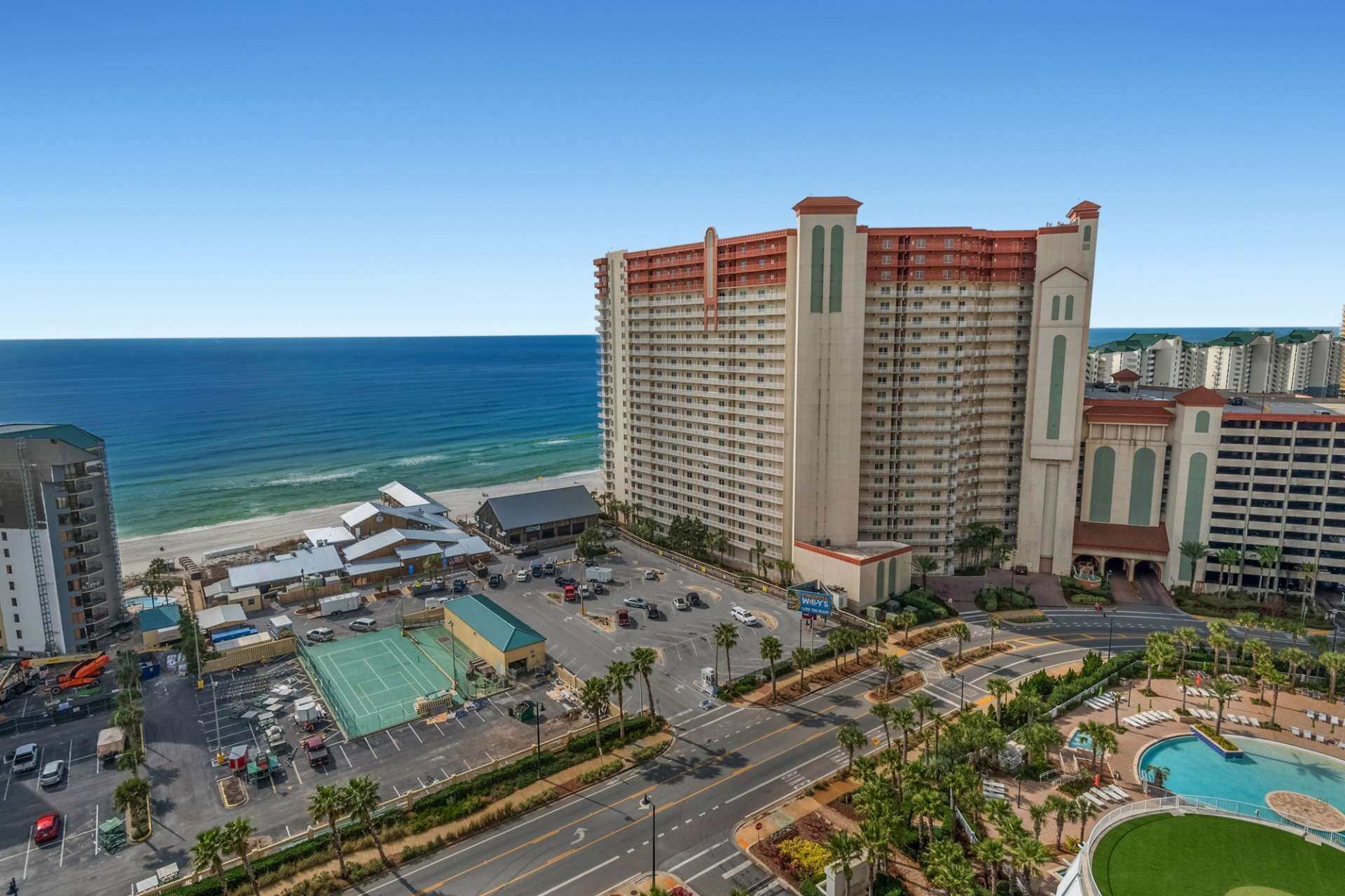 A high-rise hotel with multiple floors, a pool, and a beach view.