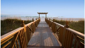 A wooden boardwalk leading to a beach with a wooden pergola at the end. - Regency Towers 703 (Panama City Beach)