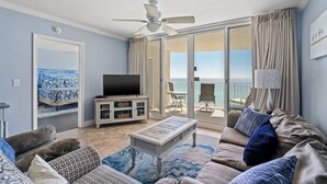 Ein Wohnzimmer mit Fernseher, einer Couch und einem Balkon mit Blick.