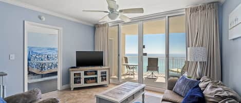 Una sala de estar con televisor, sofá y balcón con vistas.