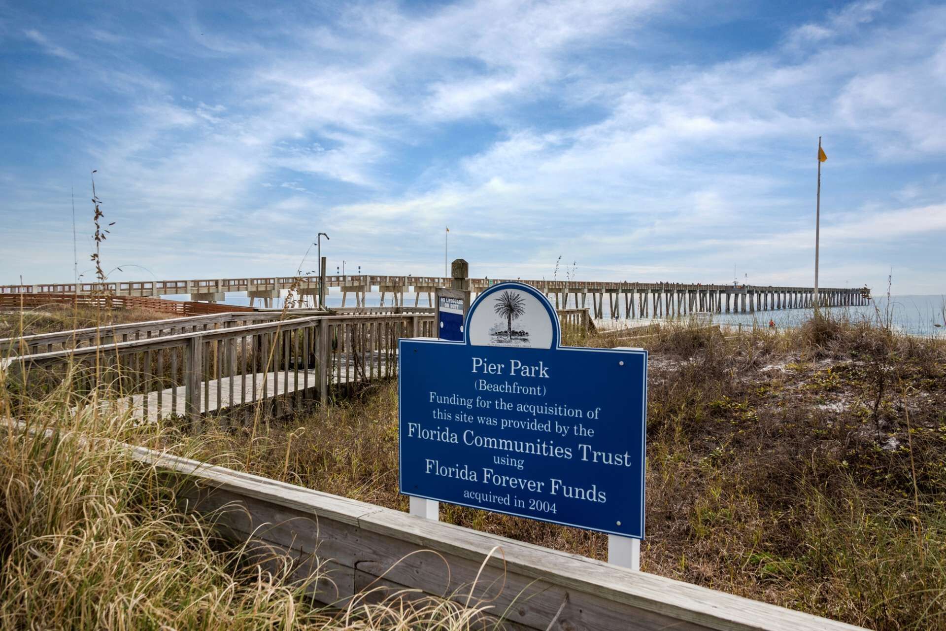 Señal de playa en Pier Park, con un muelle de madera al fondo.