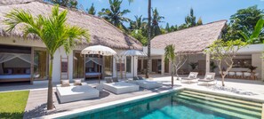 A poolside area with thatched-roof structures, white lounge areas, and palm trees. - Hidden Jewel in Bali - Villa with private chef and infinity pool (Tumbu)