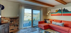 Un salon avec un canapé rouge, une cheminée, une vue sur un lac et un tableau accroché au mur.