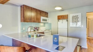 A modern kitchen with wooden cabinets, a white countertop, and a built-in microwave. There is a sink with a faucet, and a blue welcome sign on the countertop. - Stunning Lake Dillon and Keystone Views from a Cozy Mountain Retreat (Dillon)
