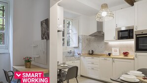 Eine moderne Küche mit weißen Schränken, einer Mikrowelle, einem Backofen und einem Essbereich mit Tisch und Stühlen.